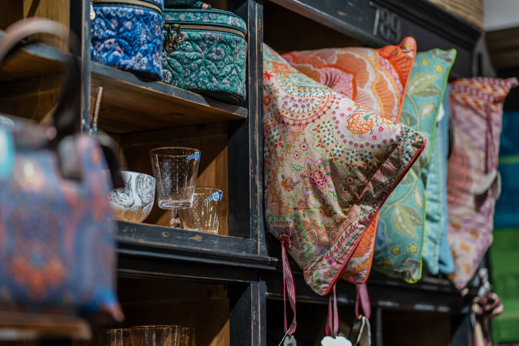 Bunte Kissen und Glaswaren in einem Regal